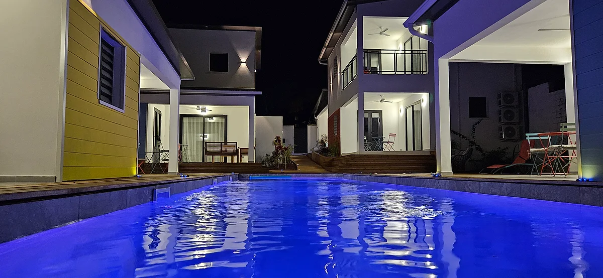 La piscine illuminée en bleu, la nuit, entre les suites