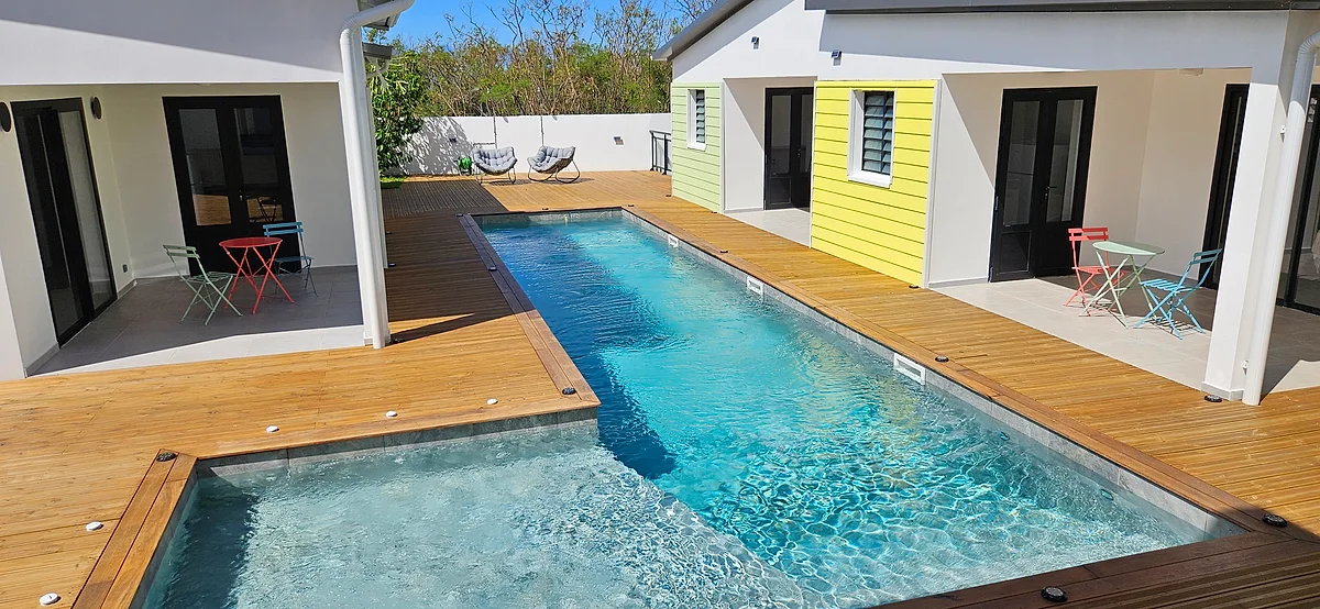 La piscine de 13,50 m bordée de bois, devant les suites colorées